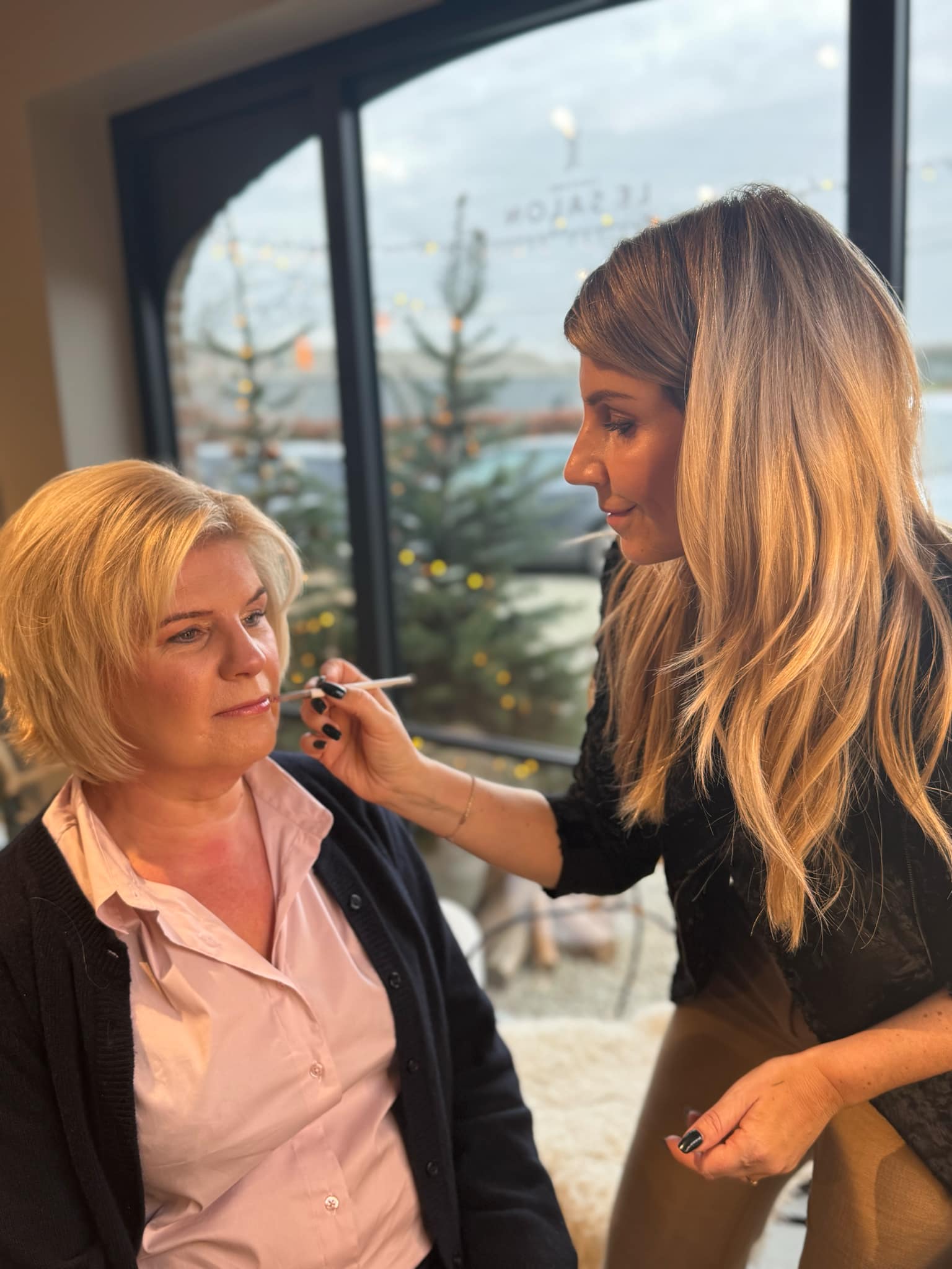 Kapster brengt lipgloss aan bij een klant